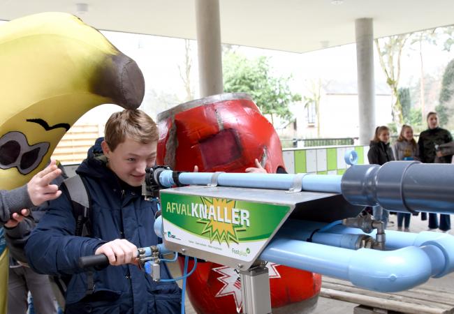 kind staat met banaan mascotte aan de afvalknaller