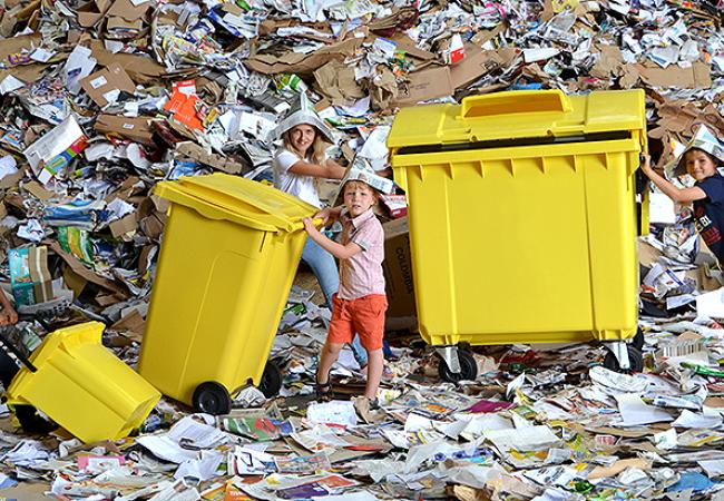 Kindjes staan rond papiercontainers
